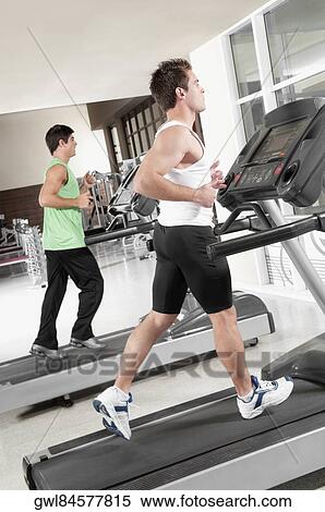 Two men running on treadmills View Large Photo Image Stock Photography - Two men running on treadmills. Fotosearch