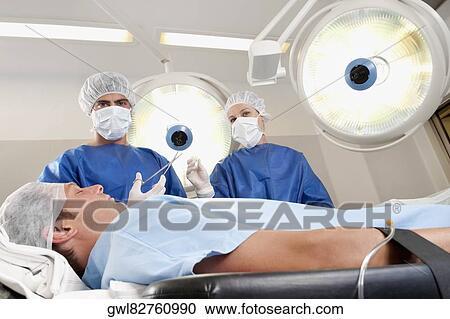 Two surgeons operating a patient in an operating room View Large Photo Image Stock Image - Two surgeons operating a patient in an operating room. Fotosearch