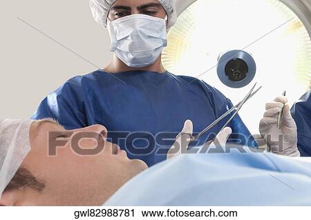 Two surgeons operating a patient in an operating room View Large Photo Image Stock Image - Two surgeons operating a patient in an operating room. Fotosearch