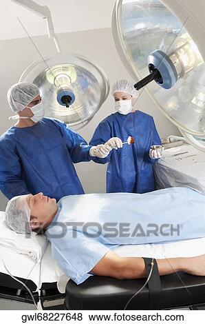 Two surgeons operating a patient in an operating room View Large Photo Image Stock Photo - Two surgeons operating a patient in an operating room. Fotosearch