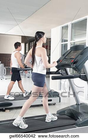 Woman and a man walking on treadmills View Large Photo Image Stock Image - Woman and a man walking on treadmills. Fotosearch