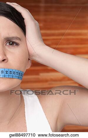 Woman covering her mouth with a tape measure View Large Photo Image Stock Image - Woman covering her mouth with a tape measure. Fotosearch