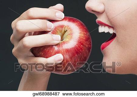 Stock Photo - Woman eating a red apple and smiling. Fotosearch