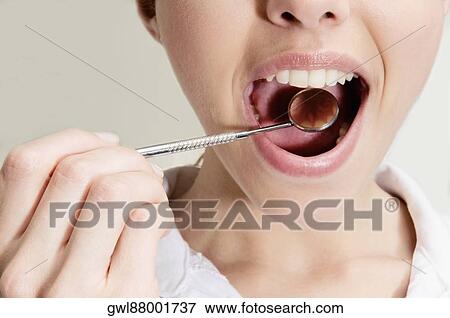 Woman examining her teeth with angled mirror View Large Photo Image Stock Photo - Woman examining her teeth with angled mirror. Fotosearch