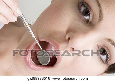 Woman examining her teeth with angled mirror View Large Photo Image Stock Photograph - Woman examining her teeth with angled mirror. Fotosearch