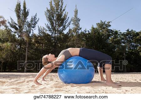 Woman exercising with a fitness ball on the beach View Large Photo Image Stock Photo - Woman exercising with a fitness ball on the beach. Fotosearch