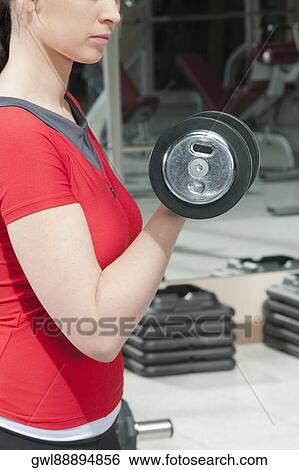 Woman exercising with dumbbells in a gym View Large Photo Image Stock Photograph - Woman exercising with dumbbells in a gym. Fotosearch