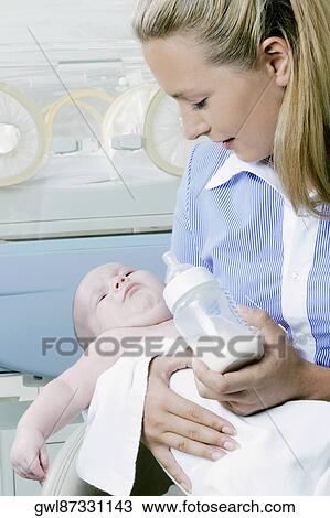 Woman feeding her baby from a milk bottle View Large Photo Image Stock Image - Woman feeding her baby from a milk bottle. Fotosearch