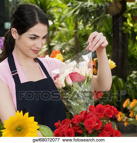 Woman holding a bouquet of flowers and smiling in a greenhouse View Large Photo Image Stock Photo - Woman holding a bouquet of flowers and smiling in a greenhouse. Fotosearch