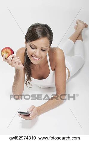 Woman holding a red apple and using a mobile phone View Large Photo Image Stock Image - Woman holding a red apple and using a mobile phone. Fotosearch