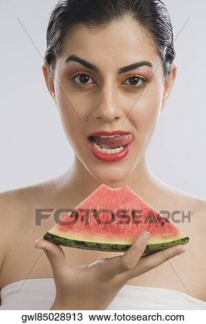 Woman holding a slice of watermelon and licking lips View Large Photo Image Stock Image - Woman holding a slice of watermelon and licking lips. Fotosearch