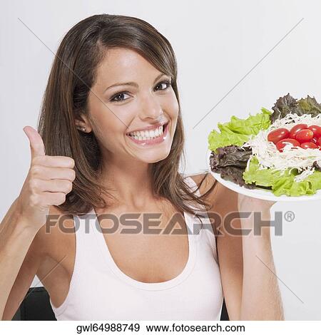 Woman making a thumbs up sign with a plate of salad View Large Photo Image Stock Photo - Woman making a thumbs up sign with a plate of salad. Fotosearch