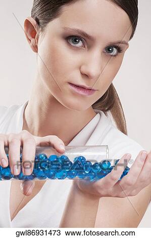 Stock Image - Woman pouring bath beads on her palm. Fotosearch