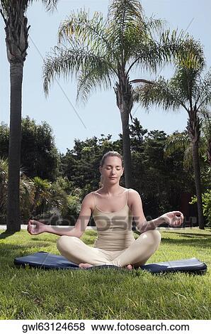 Woman practicing yoga in a park View Large Photo Image Stock Photo - Woman practicing yoga in a park. Fotosearch
