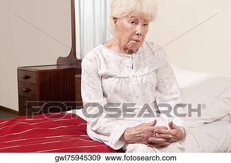 Woman sitting on the bed and looking serious View Large Photo Image Stock Photo - Woman sitting on the bed and looking serious. Fotosearch