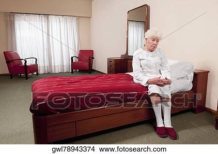 Woman sitting on the bed in a rehabilitation center View Large Photo Image Picture - Woman sitting on the bed in a rehabilitation center. Fotosearch