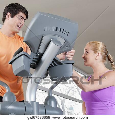 Woman talking to a man working out on a stepping machine in a gym View Large Photo Image Stock Photo - Woman talking to a man working out on a stepping machine in a gym. Fotosearch