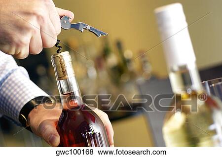 Close-up of a man unscrewing cork of a wine bottle View Large Photo Image Stock Photo - Close-up of a man unscrewing cork of a wine bottle. Fotosearch