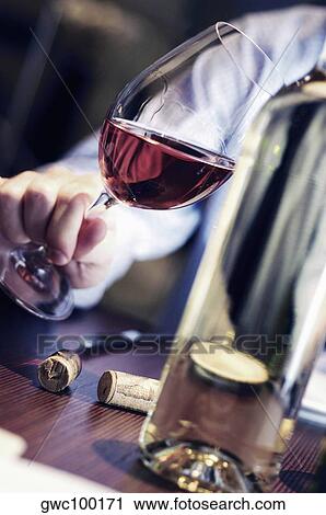 Stock Image - Close-up of a person's hand holding a glass of wine. Fotosearch