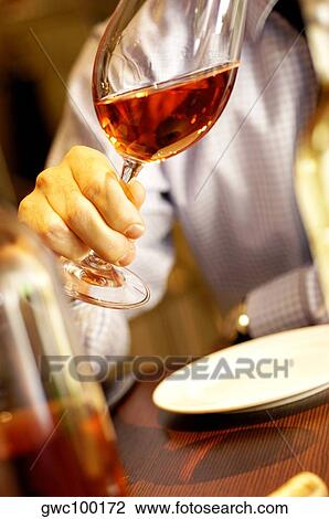 Stock Image - Close-up of a person's hand holding a glass of wine. Fotosearch