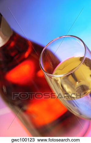 Stock Image - Close-up of a wine bottle with champagne in a champagne flute. Fotosearch