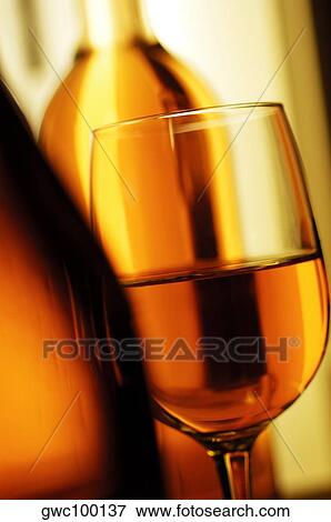 Stock Photo - Close-up of a wineglass with two wine bottles. Fotosearch