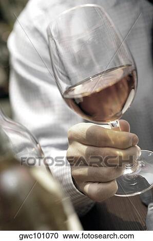 Stock Image - Close-up of a person's hand holding a glass of wine. Fotosearch