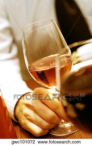 Close-up of a person's hand holding a glass of wine View Large Photo Image Stock Image - Close-up of a person's hand holding a glass of wine. Fotosearch