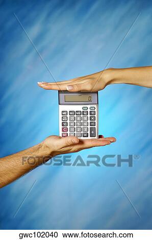 Stock Image - Close-up of a man and a woman's hands holding a calculator. Fotosearch