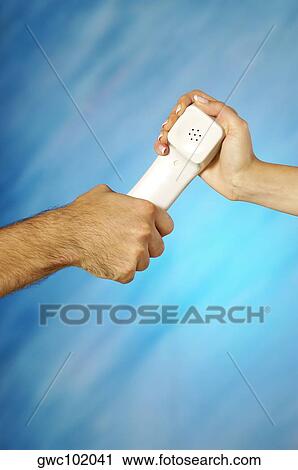 Stock Image - Close-up of a man and a woman's hands holding a telephone receiver. Fotosearch