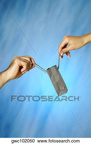 Stock Image - Close-up of a man and a woman's hands holding a shopping bag. Fotosearch