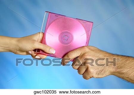 Stock Photography - Close-up of a man and a woman's hands holding a compact disk. Fotosearch