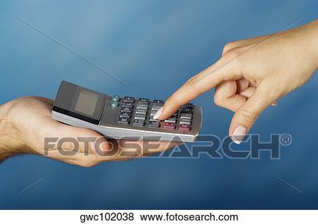 Stock Photo - Close-up of a man holding a calculator with a woman's finger pressing a button. Fotosearch