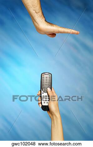 Woman's hand holding a remote control with a man's hand making stop gesture View Large Photo Image Stock Photo - Woman's hand holding a remote control with a man's hand making stop gesture. Fotosearch
