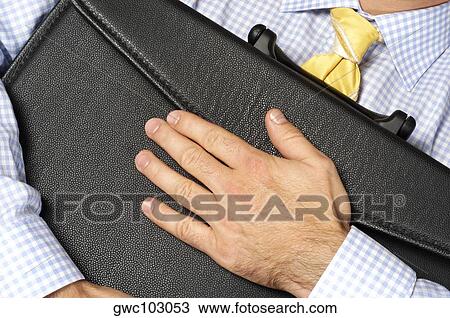 Close-up of a businessman hugging his briefcase View Large Photo Image Stock Image - Close-up of a businessman hugging his briefcase. Fotosearch