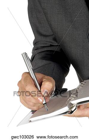 Stock Photograph - Close-up of a businessman writing on a spiral notepad. Fotosearch