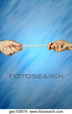 Picture - Close-up of a man and a woman's hands pulling a telephone cord. Fotosearch