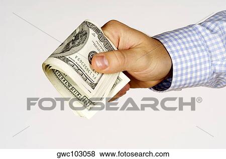Stock Photo - Close-up of a person's hand holding paper currency. Fotosearch