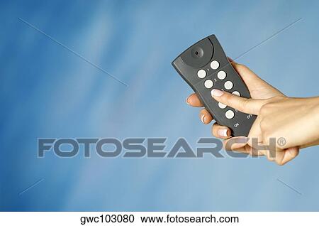 Stock Image - Close-up of a woman's hand holding a remote control. Fotosearch