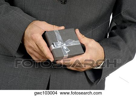 Mid section view of a businessman holding a gift View Large Photo Image Picture - Mid section view of a businessman holding a gift. Fotosearch