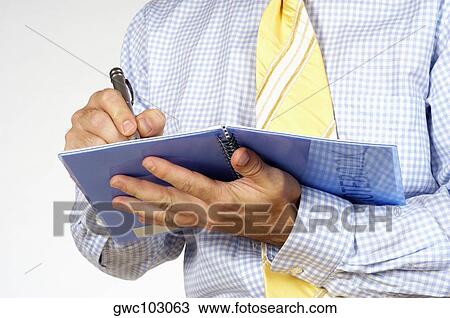 Stock Image - Mid section view of a businessman writing in a notebook. Fotosearch