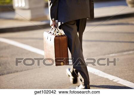 Stock Image - Man crossing the street holding a briefcase, Washington DC, USA. Fotosearch