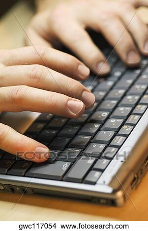 Picture - Close-up of a person's fingers using a laptop. Fotosearch