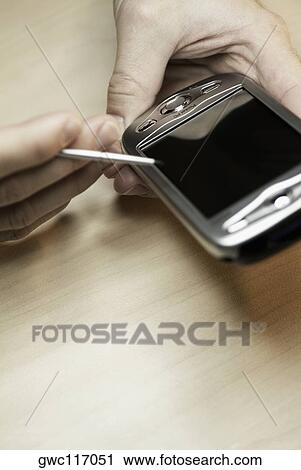 Stock Image - Close-up of a person's hand using a personal data assistant. Fotosearch