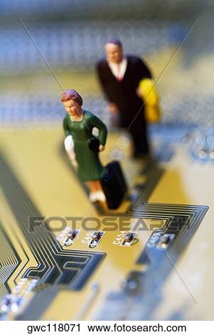 Stock Image - High angle view of the figurine of a woman and a man on a circuit board. Fotosearch
