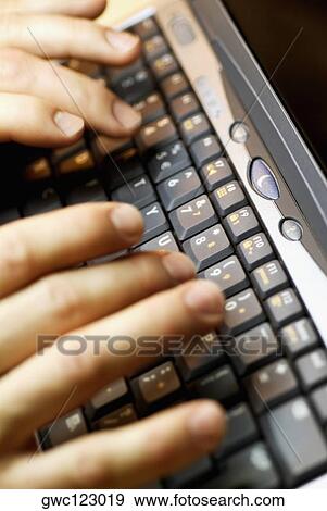 Stock Photo - Close-up of a person's fingers using a laptop. Fotosearch