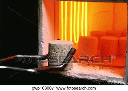 Stock Photo - Close-up of an iron rod holding a concrete block near a blast furnace. Fotosearch