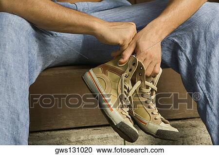 Stock Image - Close-up of a person's hand holding a pair of canvas shoe. Fotosearch