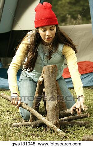Stock Photo - Close-up of a young woman adjusting firewood. Fotosearch