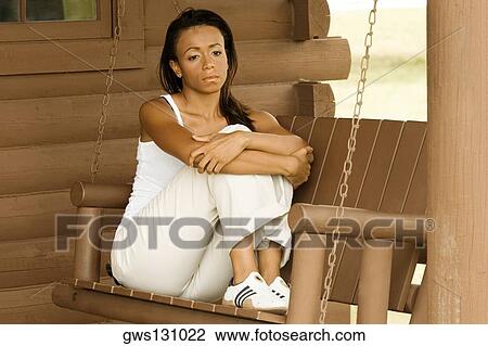 Close-up of a young woman sitting on a porch swing View Large Photo Image Stock Image - Close-up of a young woman sitting on a porch swing. Fotosearch